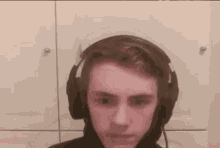 a young man wearing headphones is looking at the camera and making a funny face .