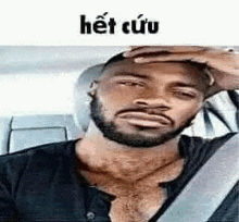 a man with a beard is sitting in the back seat of a car holding his head .