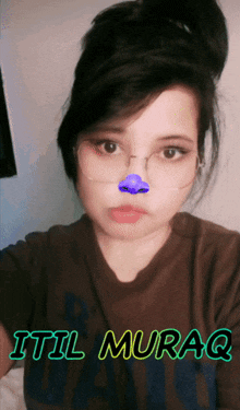 a girl with glasses and a purple nose has the name itil muraq on her shirt