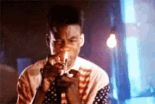 a man in an american flag shirt is smoking a cigarette in a dark room .