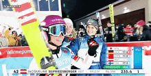 two skiers wearing scheuer goggles are hugging and smiling