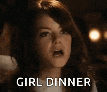 a woman is looking at a plate of food with the words `` girl dinner '' written next to her .