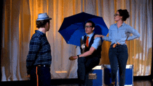 a man holding a blue umbrella talks to a woman