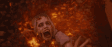 a woman is laying in a pile of burning rocks with her mouth open .