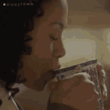 a close up of a woman drinking from a cup with the hashtag #diggstown