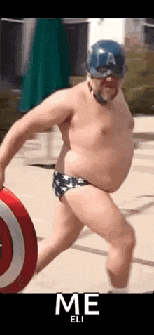 a shirtless man in swim trunks and a captain america hat is holding a shield .