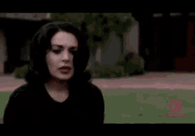 a woman with black hair and red lips is standing in a grassy field with her mouth open .
