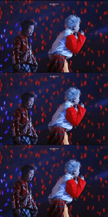 a man in a red plaid skirt is singing into a microphone on stage