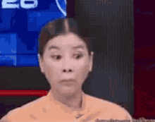 a woman is making a funny face while sitting in front of a television .