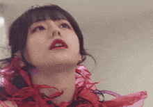 a close up of a woman 's face with red ribbons around her neck