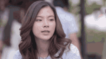 a close up of a woman 's face with long hair and a blue shirt .