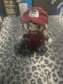 a stuffed mario is sitting on a leopard print bedspread