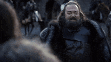 a man with a beard wearing a fur coat is smiling