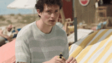 a man sitting on a beach holding a lighter in his hand