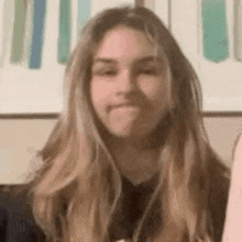 a woman with long blonde hair is making a funny face .
