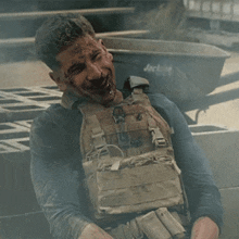 a man in a tactical vest is laughing in front of a wheelbarrow that says jackson on it