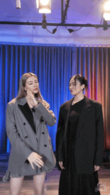 two women standing next to each other in front of a blue curtain and a sign that says girly girl
