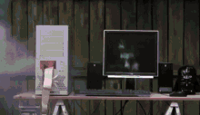 a computer is on a desk with a darth vader bag in the background