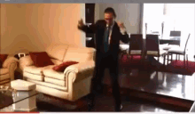 a man in a suit and tie is dancing in a living room with a white couch