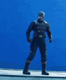 a man in a superhero costume is standing on a blue surface with his arms outstretched .