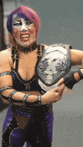 a woman in a purple outfit is holding a wrestling championship belt