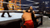 two men are wrestling in a wrestling ring while a referee watches .