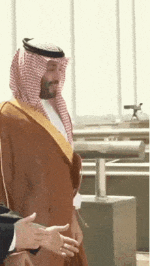 a man in a traditional arabic dress is shaking hands with another man in a suit .