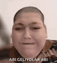 a man with a shaved head is making a funny face with the words abi geliyolar abi written below him