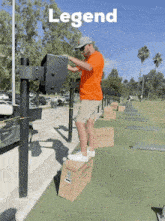 a man in an orange shirt is standing on a box in front of a sign that says legend on it