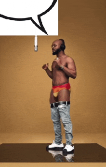 a shirtless man singing into a microphone while wearing headphones