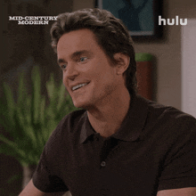 a man is smiling in front of a hulu logo