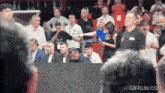 a man in a black adidas shirt stands in front of a crowd of people