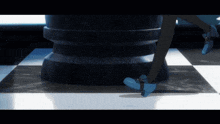 a person wearing blue shoes is standing on a checkered floor next to a chess piece