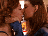a close up of two women kissing with a blurred background