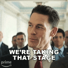 a man in a suit and tie with the words we 're taking that stage