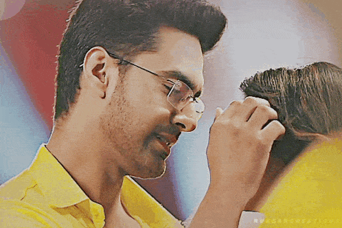 a man wearing glasses is touching a woman 's hair .