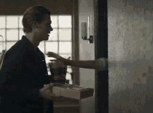 a man is holding a box of food and talking to a woman .