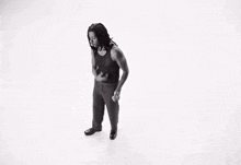 a black and white photo of a man in a tank top and pants dancing .