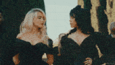 two women in black dresses are standing next to each other in a crowd