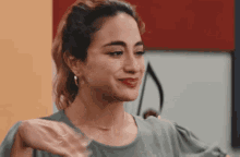 a woman in a green shirt is smiling with her hand outstretched