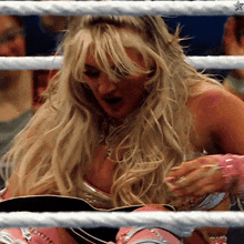a blonde woman is sitting in a boxing ring with a star on the ropes
