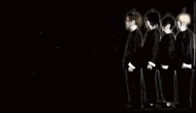 a group of people are standing next to each other in a dark room and dancing .