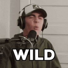 a man wearing headphones and a hat is singing into a microphone with the word wild written above him
