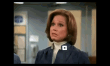 a woman in a blue jacket has a white square on her collar that says o