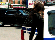 a woman stands in front of a traffic van with the number 617 on the side