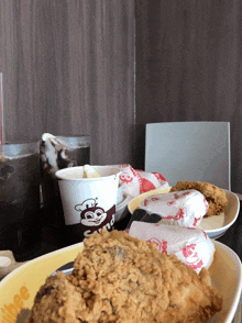 a jollibee cup sits on a table next to fried chicken