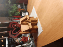 a gingerbread house sits on a wooden table next to a heart shaped candle holder