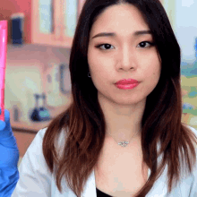a woman in a lab coat is holding a pink bottle