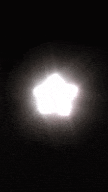 a white star shaped object is glowing in the dark .