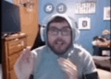 a man wearing headphones and a hoodie is sitting in front of a television .